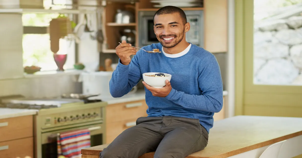 Jeune homme souriant entrain de manger équilibré