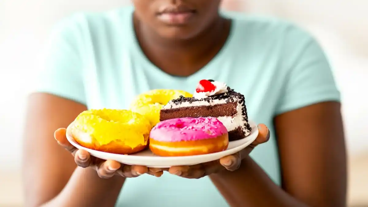 Personne tenant une assiette de pâtisseries sucrées illustrant l'addiction au sucre et la compulsion alimentaire